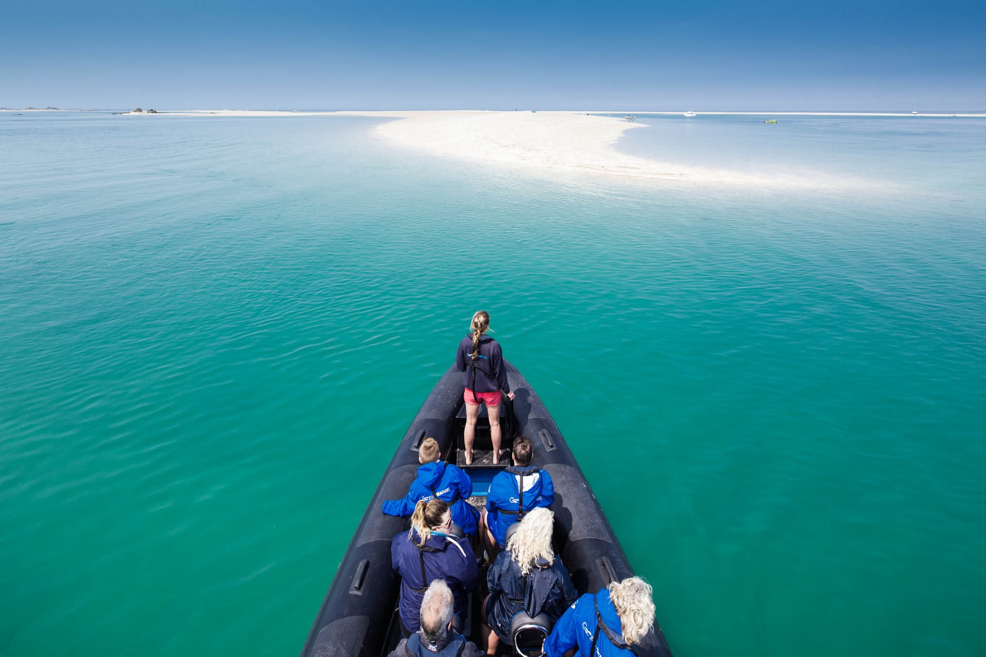 Boat Approaches Les Minquiers in Turquoise waters