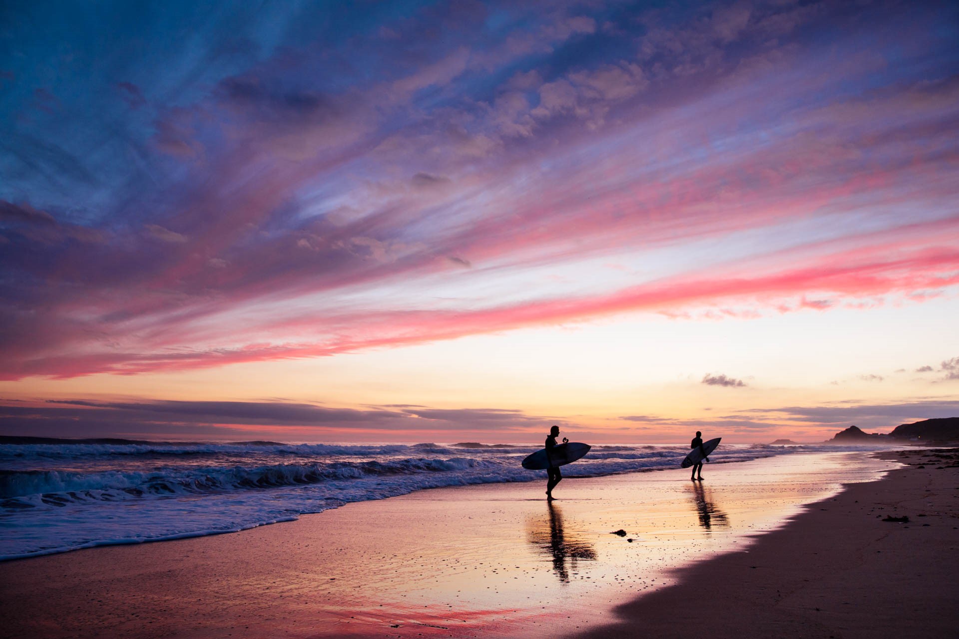 Silhouetted surfers at sunset at La Saline