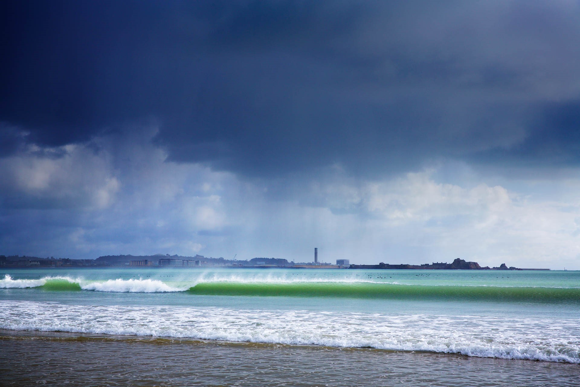 Small waves and stormy skies at St Aubin's Bay